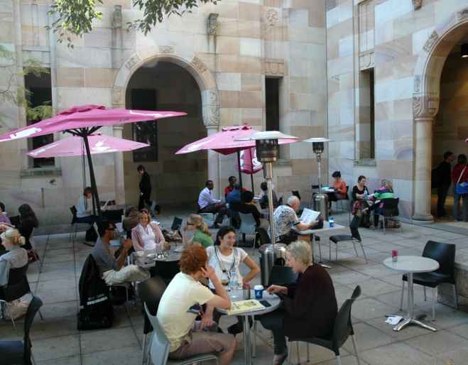 People sitting at tables in UQ forecourt drinking coffee in Brisbane's St Lucia district 