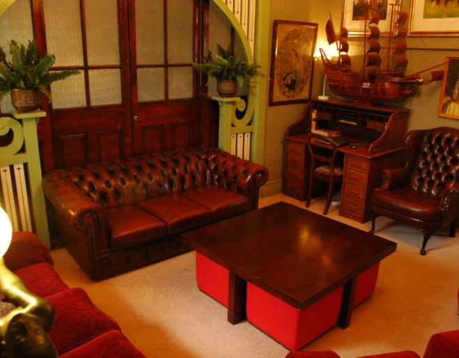 Lounge room with Chesterfield couches and antiques inside Franklin Villa guest house in Highgate Hill