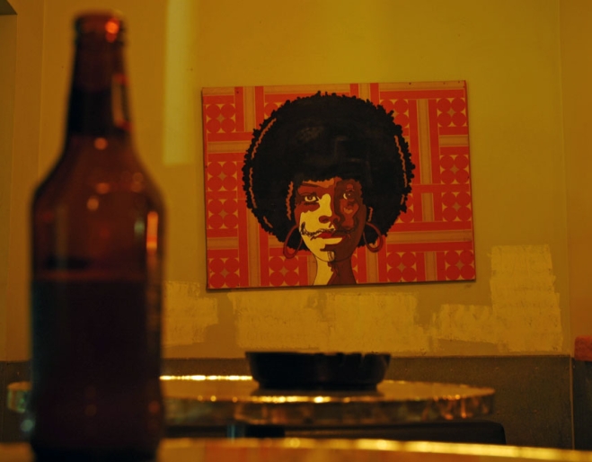 Bottle of beer on table and painting on wall inside Ric's Bar in Brisbane's Fortitude Valley