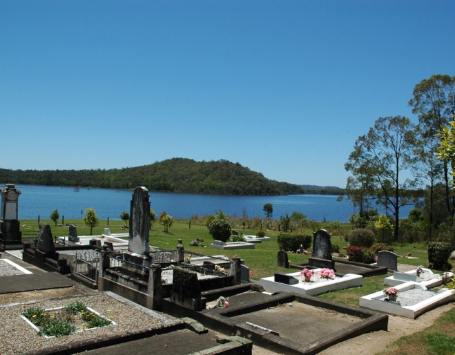 Tomb stones overlooking lake and hills in Samsonvale Cemetery .