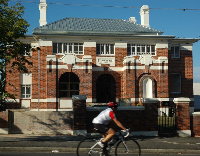 Cyclist riding past Toonarbin house in Highgate Hill