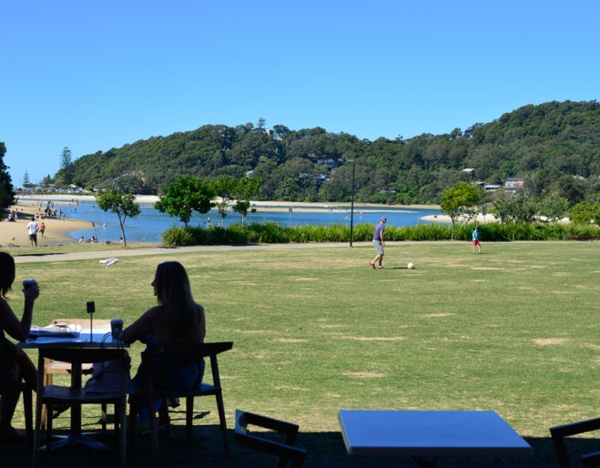 Two women overlooking Palm Beach Parklands from table outside dune cafe palm beach on the Gold Coast 