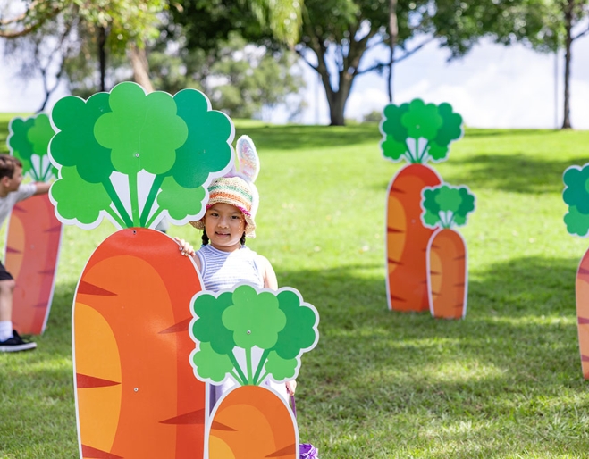 Child standing behind a decorative carrot at Easter Weekend at Roma Street Parkland