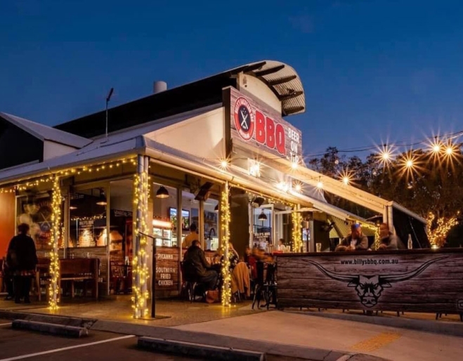 Exterior of Billy's Backyard BBQ lit up at night