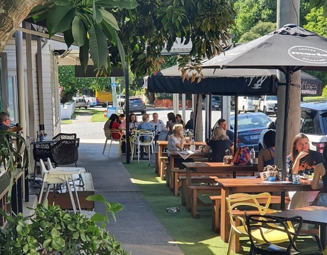 People seated under umbrellas at Double Shot Panini New Farm