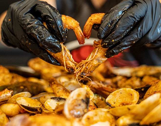 Gloved hands picking up crab claws Kickin' Inn