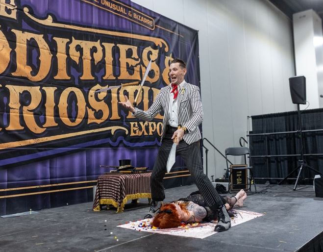 Man on stage juggling knives at the Oddities & Curiosities Expo