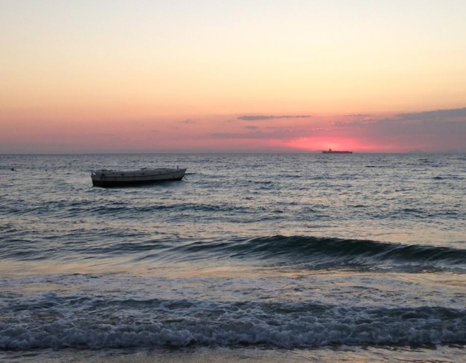 Sunset with lone rowing boat in ocean at the Glamping at Castaways resprt on Moreton Island