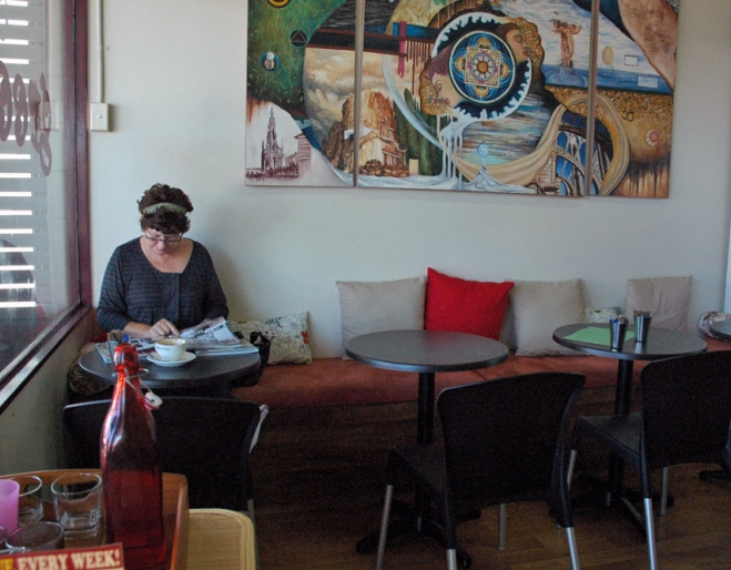 Woman sitting under painting inside Wynnum's Cafe Green Bean