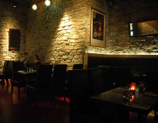 Table, chairs and sandstone wall inside O Bar in Brisbane's Spring Hill