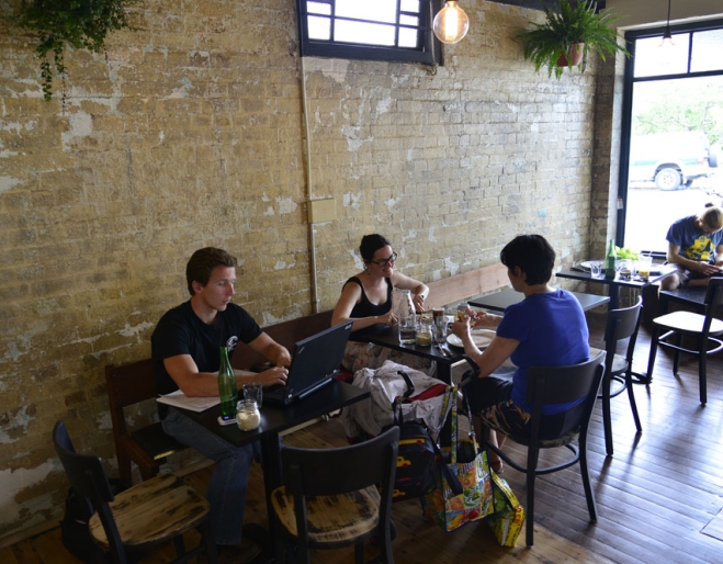 Patrons sitting inside Scout Cafe in Petrie Terrace next to exposed brick wall of old Chinaman's shop.