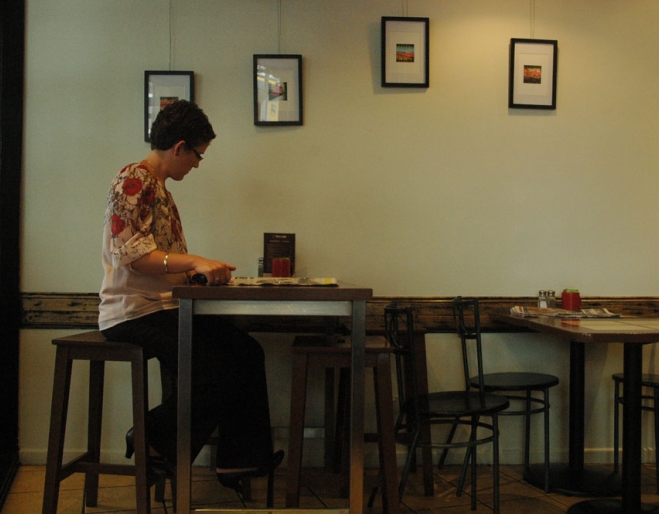 Woman sitting at table drinking a cup of coffee in Brisbane's Two Espresso cafe in Spring Hill.