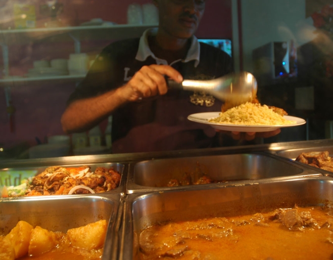 Waiter serving plate of food at hot counter inside Umdorman Sudanese Restaurant Moorooka