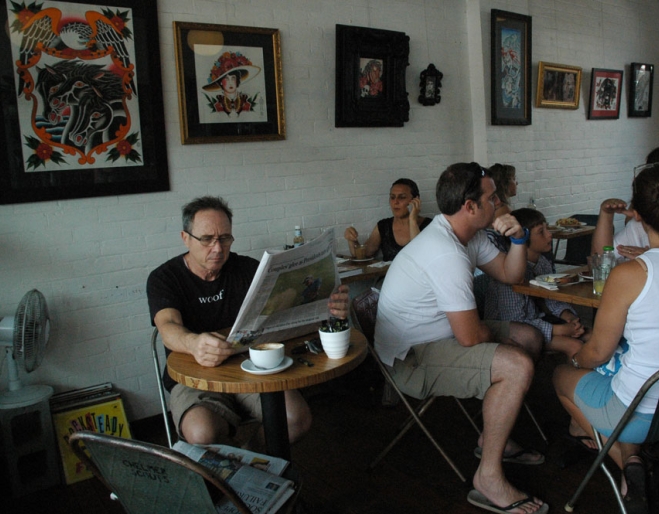 People sitting inside West End Coffee House with Aboriginal paintings on white brick walls