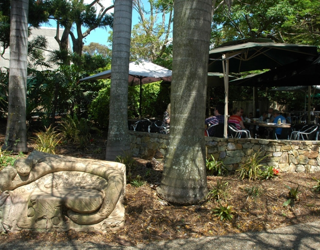 Sandstone scuptures and palm trees surring tables and chairs outside Wordsmith's cafe