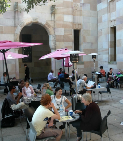 People sitting at tables in UQ forecourt drinking coffee in Brisbane's St Lucia district 