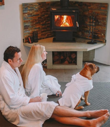 Couple in bathrooms with dog by an indoor fire at Alure Stanthorpe