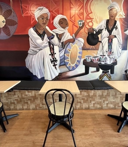 Tables and chairs in front of African mural at wall Afro Restaurant, Moorooka 
