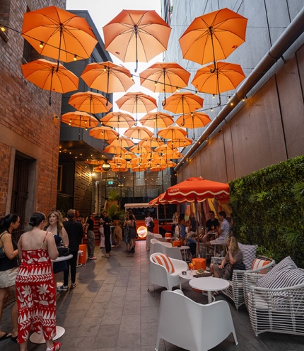 People seated under orange umbrellas in Doughcraft Lane