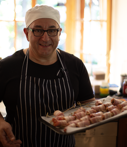 Chef Robert Bousamra standing in kitchen holding tray of food