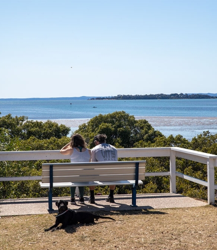 Two people sitting on a bench at a rest stop along the Lota Manly Walk