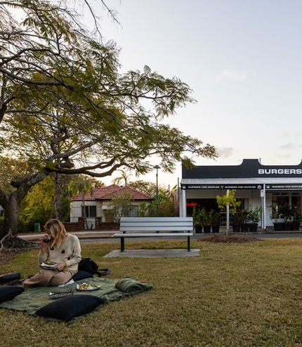 Person seated on rug outside Hashtag Burgers Ashgrove