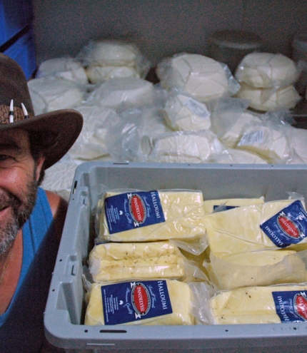 Pandelyssi next to stack of feta and haloumi cheeses inside his factory in Holland Park