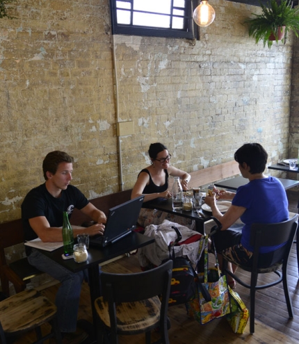 Patrons sitting inside Scout Cafe in Petrie Terrace next to exposed brick wall of old Chinaman's shop.
