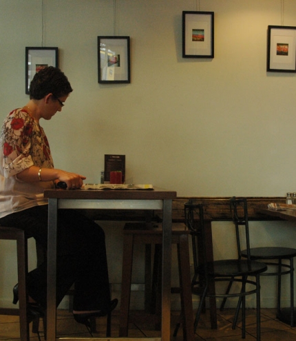Woman sitting at table drinking a cup of coffee in Brisbane's Two Espresso cafe in Spring Hill.