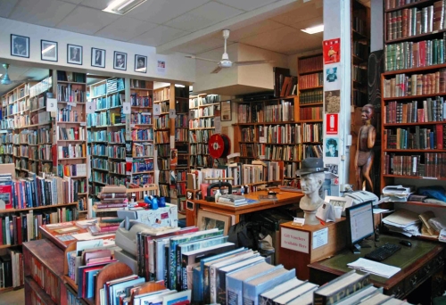 Books on shelves and on tables inside Archives Fine Books