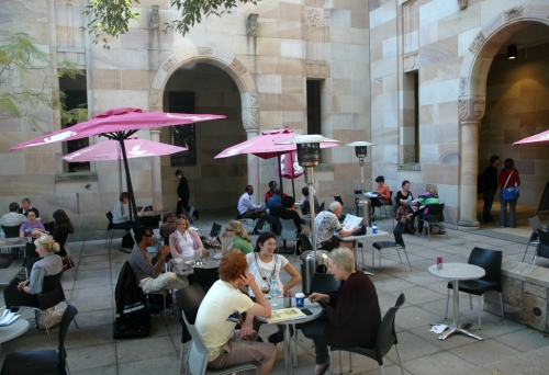 People sitting at tables in UQ forecourt drinking coffee in Brisbane's St Lucia district 