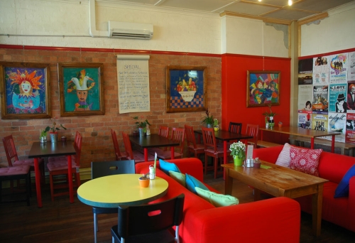 Red couches and artwork on brick wall inside Java Lounge Cafe in Paddington.