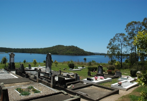 Tomb stones overlooking lake and hills in Samsonvale Cemetery .