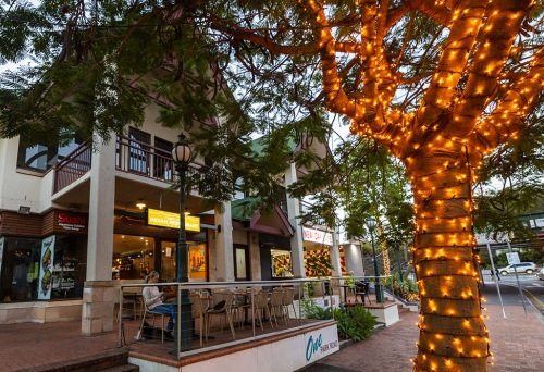 Woman sitting at table next to fairy-lit tree outside A Night in India Milton