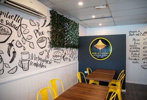 Yellow chairs with brown wooden tables inside Banh Mi Factory Zillmere