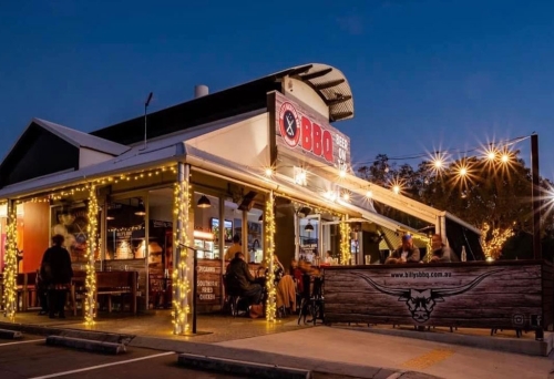 Exterior of Billy's Backyard BBQ lit up at night