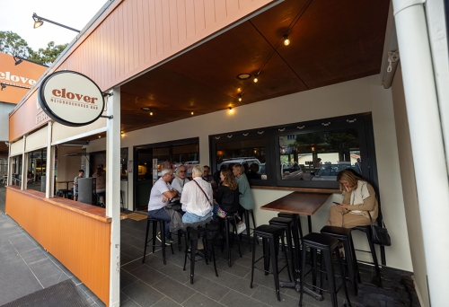 Exterior of Clover Neighbourhood Bar Holland Park with people sitting on bar seats