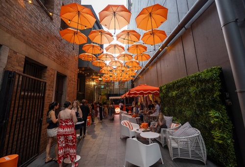 People seated under orange umbrellas in Doughcraft Lane