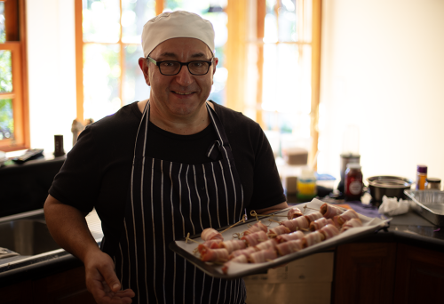 Chef Robert Bousamra standing in kitchen holding tray of food