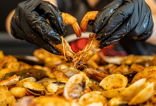 Gloved hands picking up crab claws Kickin' Inn