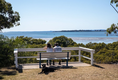 Two people sitting on a bench at a rest stop along the Lota Manly Walk