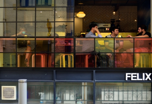 People sitting in Felix Espresso seen through coloured glass on Burnett Lane 