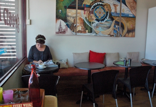 Woman sitting under painting inside Wynnum's Cafe Green Bean