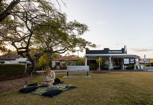 Person seated on rug outside Hashtag Burgers Ashgrove