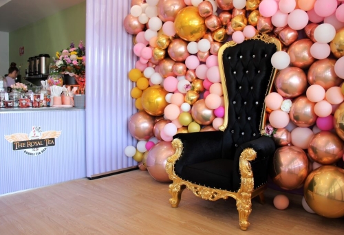 Black and gold throne in front of a wall of balls inside The Royal Tea Stafford