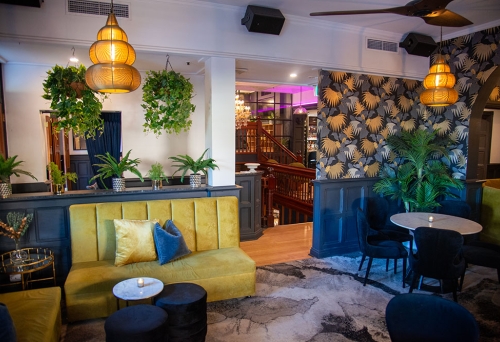 Yellow banquette, wallpaper and chandelier at Trove Bar