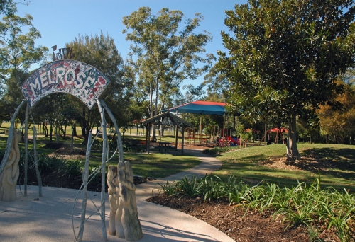 Melrose Park sign at entrance of Melrose Park Wooloowin with playground in the background.
