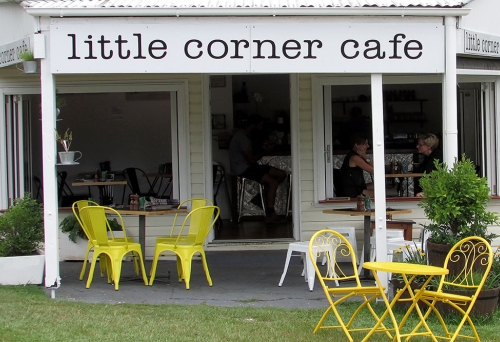 Little Corner Cafe Wooloowin's shop front with yellow cast iron seats and tables in front yard 