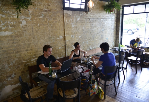 Patrons sitting inside Scout Cafe in Petrie Terrace next to exposed brick wall of old Chinaman's shop.