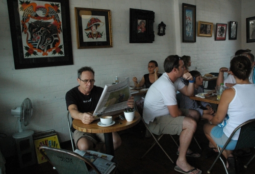 People sitting inside West End Coffee House with Aboriginal paintings on white brick walls